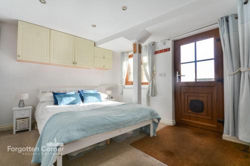 a bedroom with a bed with blue pillows and a window at The Wash House in Torpoint