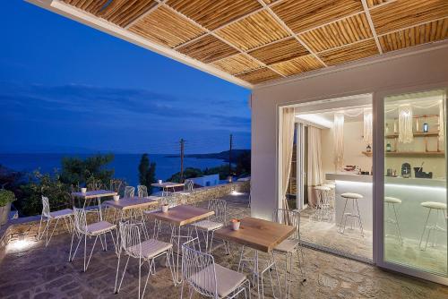 a patio with tables and chairs and a view of the ocean at Canal Suites Kythnos in Kanala