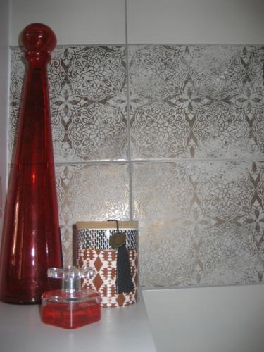 un vase rouge assis au-dessus d'un comptoir avec une bougie dans l'établissement Agréable & Lumineux, à La Rochelle