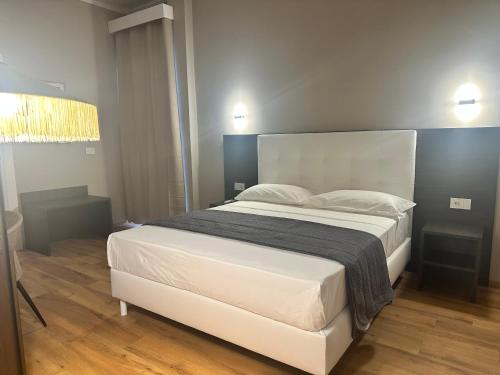 a bedroom with a large bed with white sheets and pillows at Sunset Guest House in Reggio Calabria