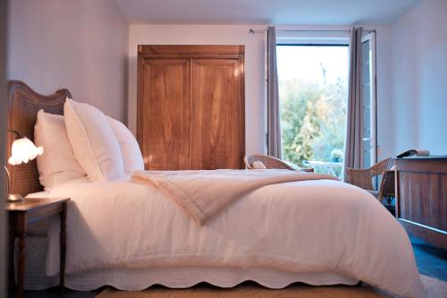 a bedroom with a large white bed with a window at Patio des Rêves - Charme au cœur du Gers in Aujan-Mournède