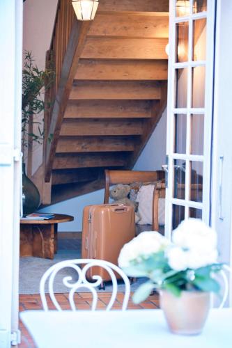a stairway with a suitcase and a chair in a room at Patio des Rêves - Charme au cœur du Gers in Aujan-Mournède