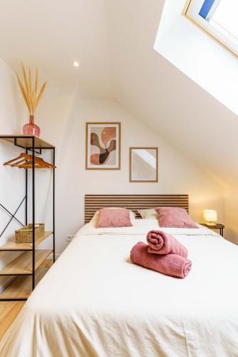 - une chambre avec un grand lit blanc et des serviettes roses dans l'établissement Studio Séduisant 2pers wifi gare, à Saint-Quentin