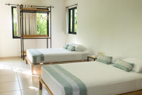 two beds in a room with two windows at Yauik in Tequesquitengo
