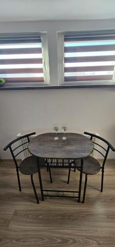 a wooden table with two wine glasses and two chairs at Studio dla DWOJGA in Kętrzyn