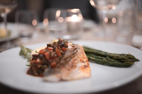 a white plate with a piece of meat and asparagus at Patio des Rêves - Charme au cœur du Gers in Aujan-Mournède