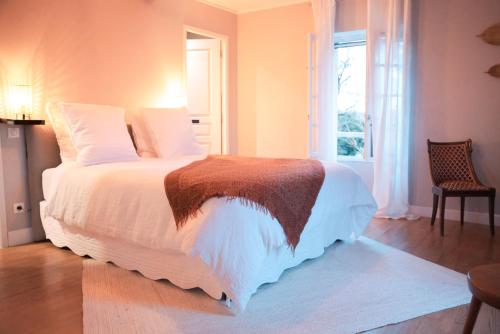 a bedroom with a bed with white sheets and a window at Patio des Rêves - Charme au cœur du Gers in Aujan-Mournède