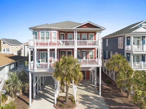 a large house with palm trees in front of it at Cherry Bomb Private heated Pool, Elevator in Ocean Isle Beach