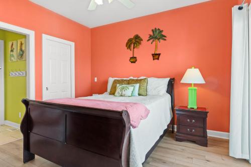 a bedroom with orange walls and a bed with a dresser at Cherry Bomb Private heated Pool, Elevator in Ocean Isle Beach
