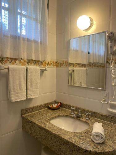 a bathroom with a sink and a mirror and towels at Hotel Solar dos Montes in Santana dos Montes
