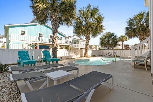 a patio with chairs and a pool with palm trees at Cherry Bomb Private heated Pool, Elevator in Ocean Isle Beach