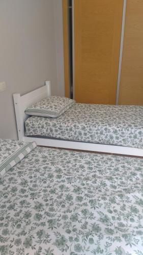 two beds are in a room with a door at Résidence avec piscine Kenz Mehdia in Kenitra