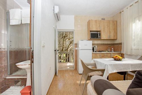 a small kitchen with a table and a white refrigerator at Apartments Oliva in Utjeha