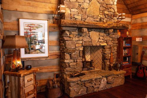 a living room with a stone fireplace in a cabin at Elk & Embers Mountain Hideaway in Waynesville