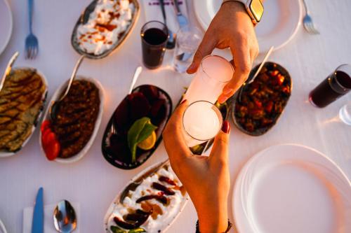 a person holding a glass of wine over a table with plates of food at Hotel Delta in Fethiye