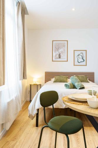 - une chambre avec un lit et une table avec une chaise verte dans l'établissement Studio Elégant 3 pers wifi, à Saint-Quentin