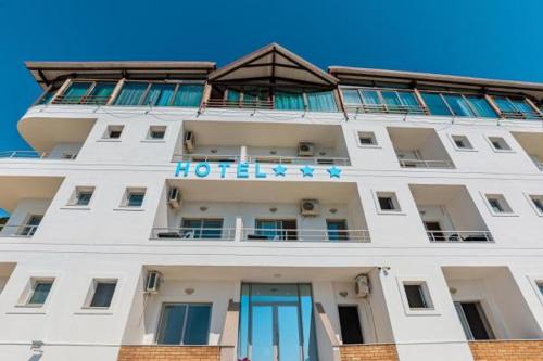a white building with a hotel sign on it at Fly Hotel in Vlorë