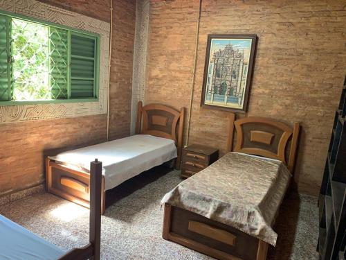 a room with two beds and two chairs and a window at Villa Domus in Barretos