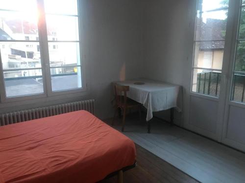 a bedroom with a bed and a table and windows at Chambre chez l'habitant dans un appartement à 2 pas de la gare SNCF et à 300m de la gare routière in Creil