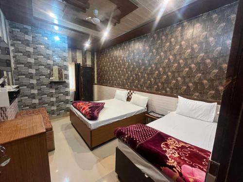 a bedroom with two beds and a wall with a mural at Hotel Aapno Shyam And Restaurant in Khātu