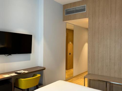a hotel room with a bed and a desk and a television at Chi in Barcelona