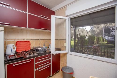 a kitchen with red cabinets and a large window at Apartments Oliva in Utjeha