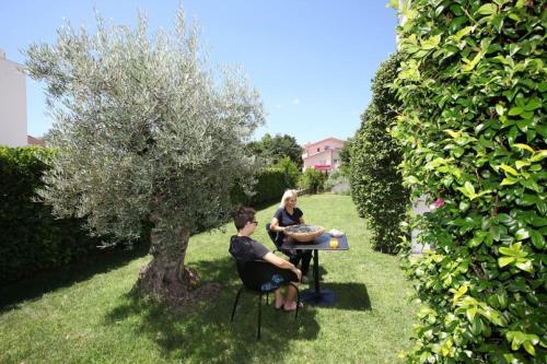 a man and woman sitting at a table under a tree at Hotel IN in Međugorje