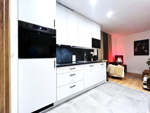 une cuisine avec des armoires blanches et un appareil noir dans l'établissement L'Etoile du Vignoble au cœur d'un ranch alsacien sur la route des Vins, à Dambach-la-Ville