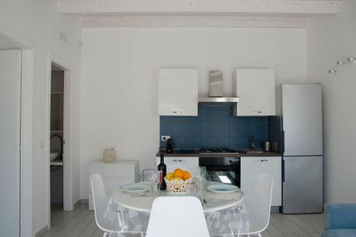 a kitchen with a table and chairs and a kitchen with blue at Almaga Apartments - San Lorenzo, Marzamemi in Noto