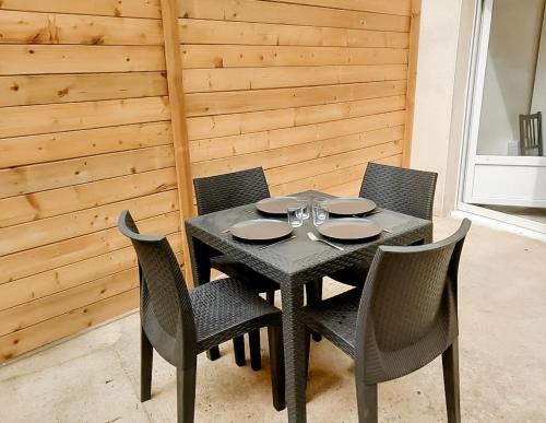 une table avec quatre chaises et une table noire avec des verres à vin dans l'établissement Evasion, Appartement avec terrasse, à Reims