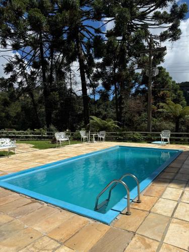 a blue swimming pool with tables and chairs at Hotel Refúgio Alpino in Campos do Jordão