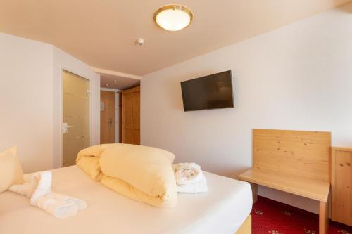 a bedroom with a bed and a television on the wall at Hotel Pinzger Tux in Tux