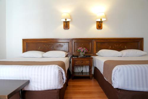 a room with two beds and a table with flowers at Hotel de Mendoza in Guadalajara