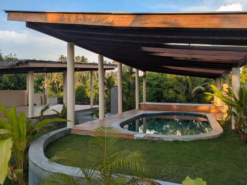 a backyard with a swimming pool and an umbrella at Remote Nest Cabins in Ahangama
