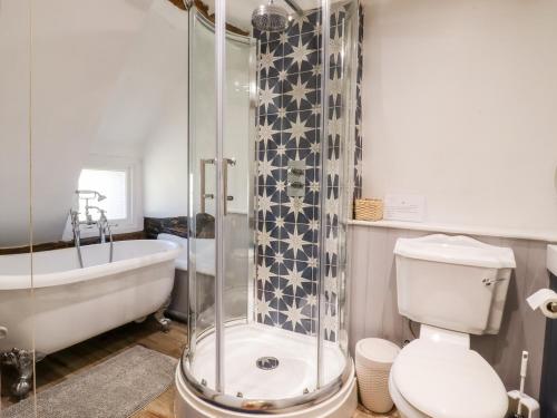 a bathroom with a shower and a toilet and a tub at 1 Harpur Cottage in Bedford