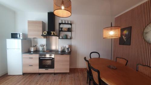 a kitchen and dining room with a table and a refrigerator at L'Astu'Cieux appartement triplex in Huelgoat