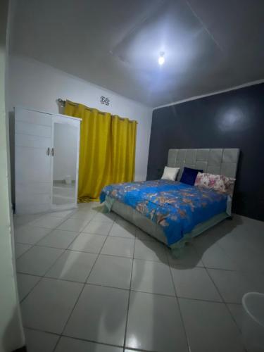 a bedroom with a bed and a yellow curtain at Mila home in Arusha