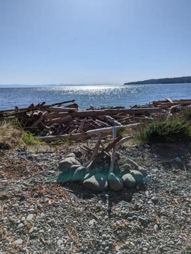 a pile of logs on the shore of a body of water at Woodside Farm Country Inn in Sooke