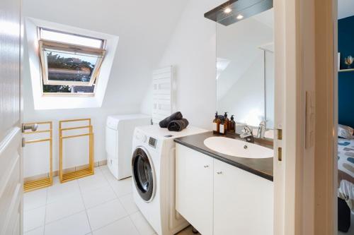 une salle de bain avec une machine à laver et un lavabo dans l'établissement Séjour Confort Mer & Littoral LE CROISIC, au Croisic