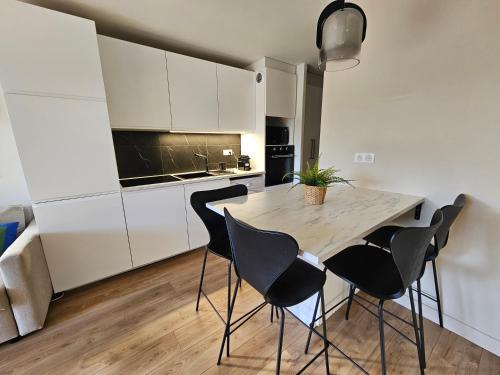 une cuisine avec des armoires blanches et une table et des chaises dans l'établissement Appartement Le Riviera, à Cannes