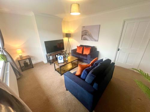 a living room with a blue couch and a tv at The Billingham House By Blue Skies Stays in Stockton-on-Tees