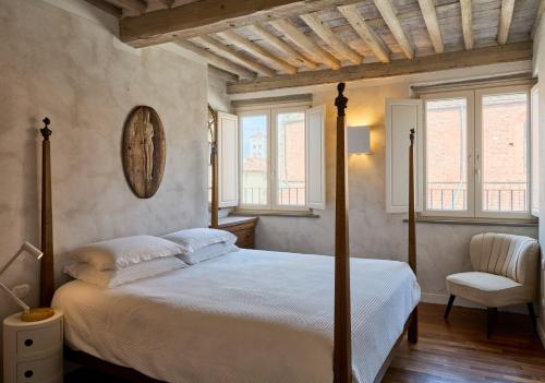 a bedroom with a bed and a chair and windows at Terrazza - A Bella Vista Apartment - Luxury in Lucca Centro in Lucca