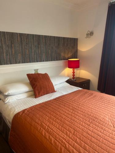 a bedroom with a large orange bed with a red lamp at The Thistle in Stranraer