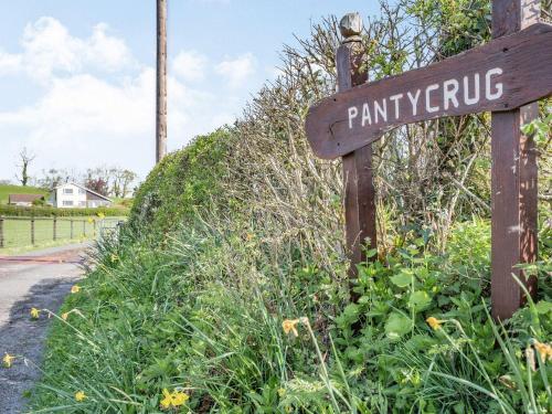 a wooden sign that reads pantryuing next to a road at Pant Y Cwtsh in Kidwelly