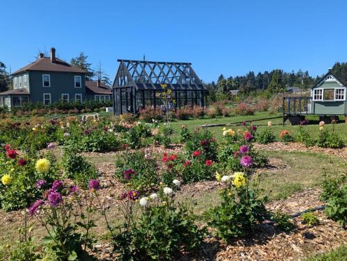 a garden with flowers in front of a house at Woodside Farm Country Inn in Sooke