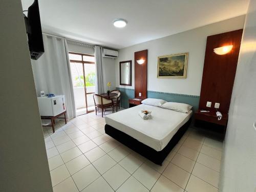 a bedroom with a bed and a table and chairs at Hotel Alvorada Taguatinga by Bsb Inn in Taguatinga