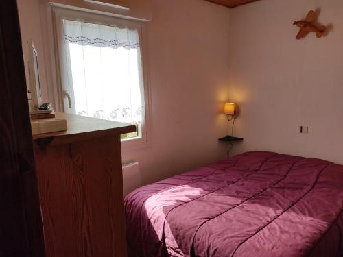 une chambre avec un lit violet et une fenêtre dans l'établissement Chez GéGé, à La Bresse