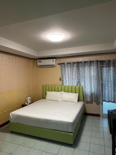 a bedroom with a green bed and a window at MAGNIFICo INN PATTAYA in Pattaya