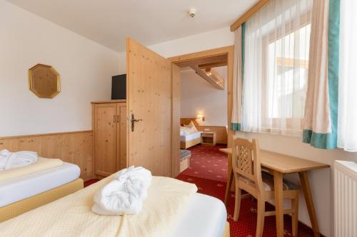 a hotel room with two beds and a table and a window at Hotel Pinzger Tux in Tux