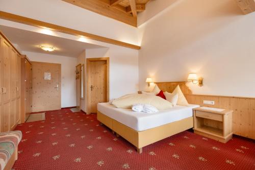 a hotel room with a bed and a red carpet at Hotel Pinzger Tux in Tux